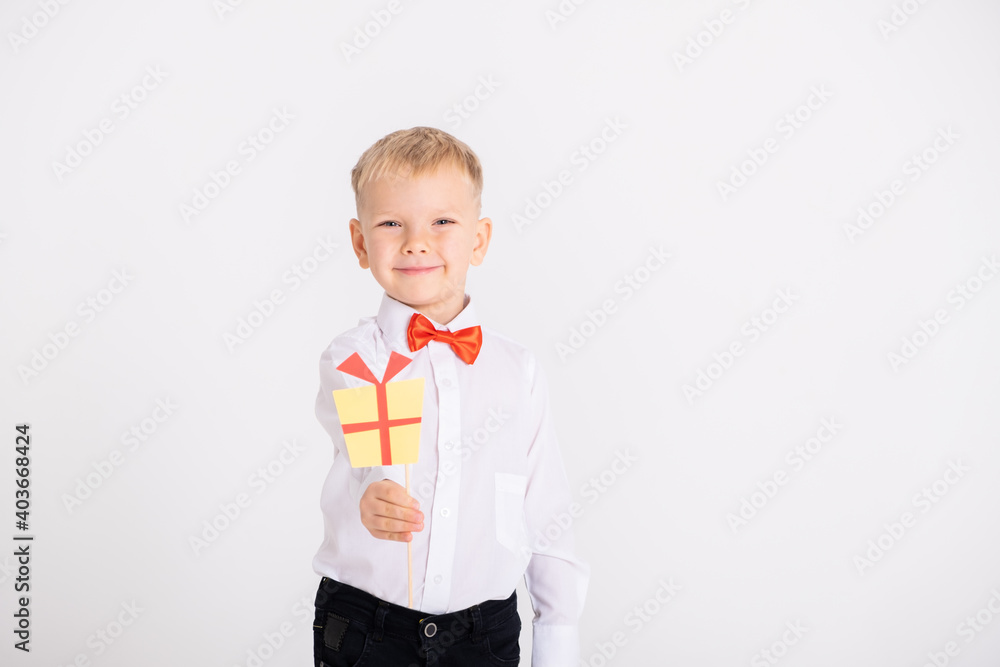 boy in suit and red bow tie holds the toppers or stikcers gift design on a white background. boy in suit and red bow tie holds the toppers or stikcers gift design on a white background.