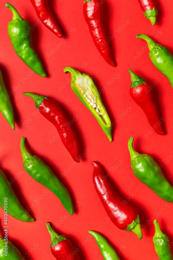 Chili peppers background. Hot red and green fresh chili peppers on red background flat lay top view. Seasoning for dish, spicy spices for cooking, cayenne pepper, food. Creative layout, chili pattern