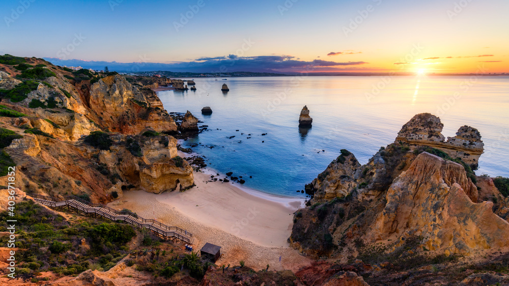 Sunrise at Camilo beach in Lagos, Algarve, Portugal. Wooden footbridge to the beach Praia do Camilo, Portugal. Picturesque view of Praia do Camilo beach in Lagos, Algarve region, Portugal. Sunrise at Camilo beach in Lagos, Algarve, Portugal. Wooden footbridge to the beach Praia do Camilo, Portugal. Picturesque view of Praia do Camilo beach in Lagos, Algarve region, Portugal.