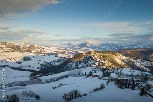 Aerial panoramic view of Ruino town in Oltrepo Pavese covered in snow at sunset