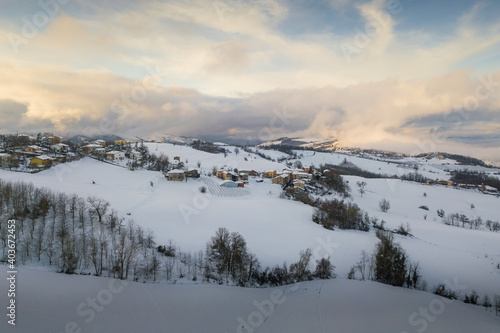 Aerial panoramic view of hills covered with snow at sunset © Michele