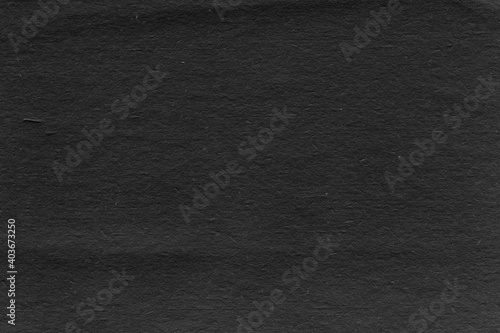 Cardboard black abstract texture close-up. Dark old paper background. Grunge concrete wall. Vintage blank wallpaper.