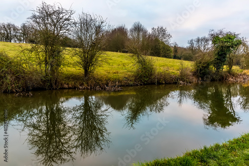 Trees lining the Grand Union Canal near Foxton Locks, UK are reflected in the water on a still winter's afternoon