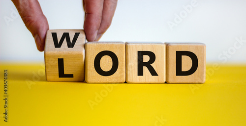 The word of the Lord symbol. Hand turns the wooden cube and changes the word 'Lord' to 'word' on a beautiful yellow table, white background. Word the Lord concept. Copy space. photo