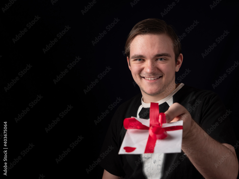 young guy in black t-shirt suit stretches out his hand with a white postcard young guy in black t-shirt suit stretches out his hand with a white postcard