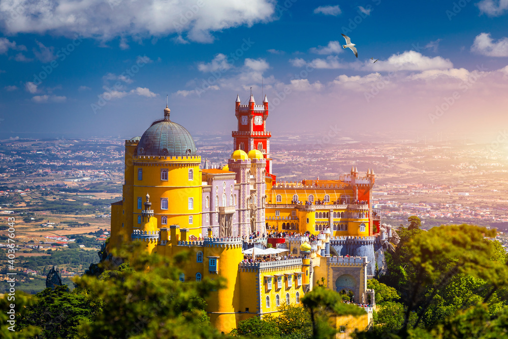 Obraz premium Famous historic Pena palace part of cultural site of Sintra against sunset sky in Portugal. Panoramic View Of Pena Palace, Sintra, Portugal. Pena National Palace at sunset, Sintra, Portugal.