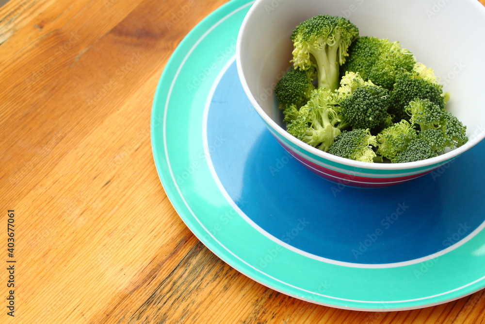 Bowl of fresh and healthy broccoli flowers on wooden table Bowl of fresh and healthy broccoli flowers on wooden table