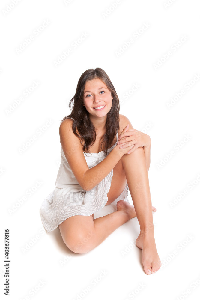 Laughing young woman sitting on the floor wearing casual summer skirt and top, isolated in front of white studio background Laughing young woman sitting on the floor wearing casual summer skirt and top, isolated in front of white studio background