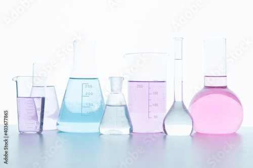 Chemical glassware with colored reagents on a white background.