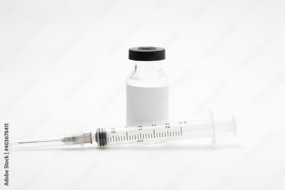 Vidro de vacina e seringa sobre a superfície branca de uma mesa. Vidro de vacina e seringa sobre a superfície branca de uma mesa.