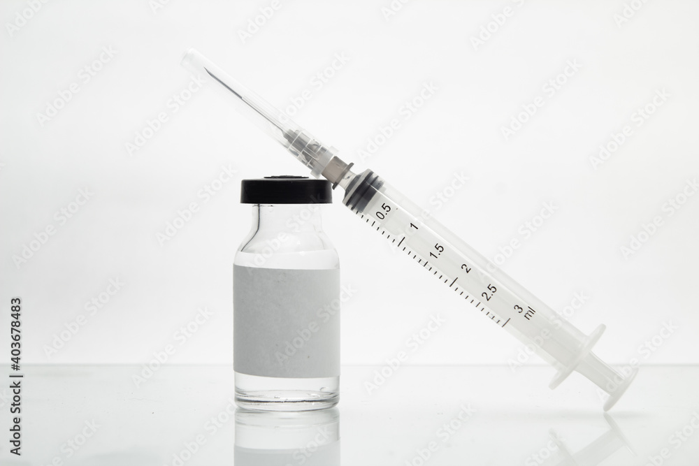 Vidro de vacina e seringa sobre a superfície branca de uma mesa. Vidro de vacina e seringa sobre a superfície branca de uma mesa.