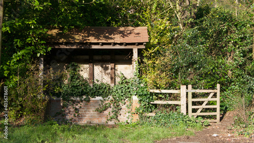 Old dilapidated bus shelter or shack in countryside with gate beside