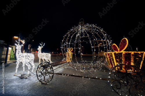 Luminous figure of a deer in harness with a carriage. Christmas story. Christmas decorations in the square.