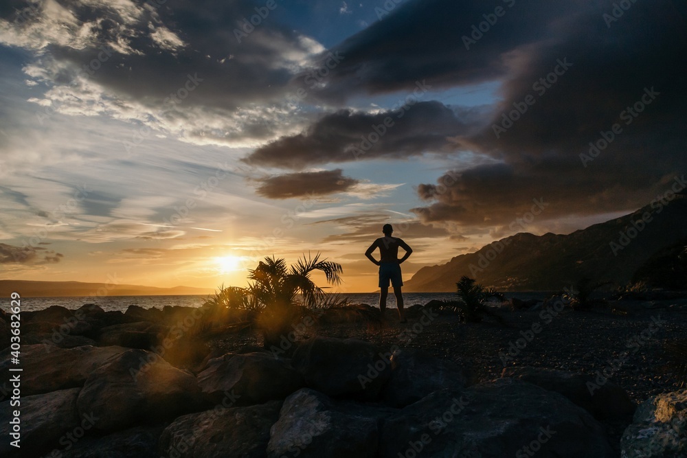 Silhouette of man over sunset on the sea and mountains background
