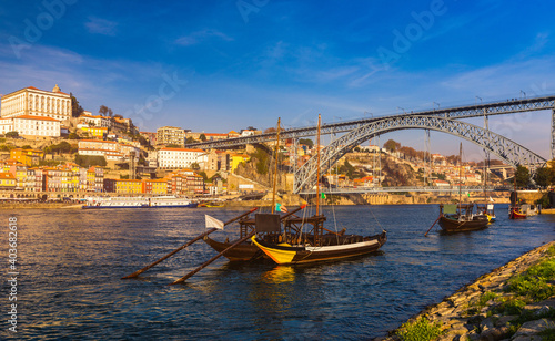 Port wine boats at the waterfront with Dom Luis bridge and the old town on the Douro River in Ribeira in the city centre of Porto in Porugal in Europe. Portugal, Porto