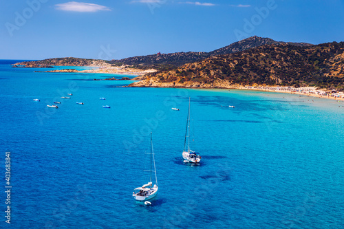 Aerial view of anchored sailing yacht in emerald sea. Aerial view of a boat. Outdoor water sports  yachting. Aerial view of anchoring yacht in open water. Ocean and sea travel and transportation