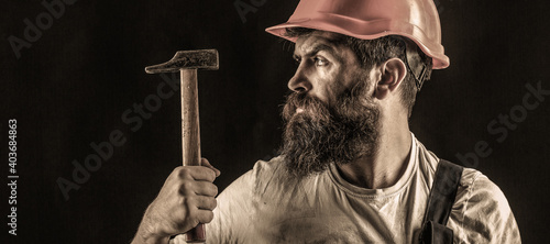 Handyman services. industry, technology, builder man, concept. Bearded man worker with beard, building helmet, hard hat. Hammer hammering. Builder in helmet, hammer, handyman photo