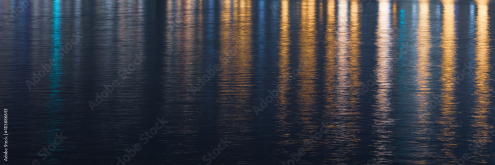Water texture with colored lights reflected in it at night