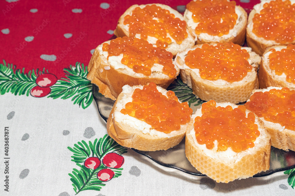 a plate of sandwiches with red caviar on a New Year's tablecloth a plate of sandwiches with red caviar on a New Year's tablecloth
