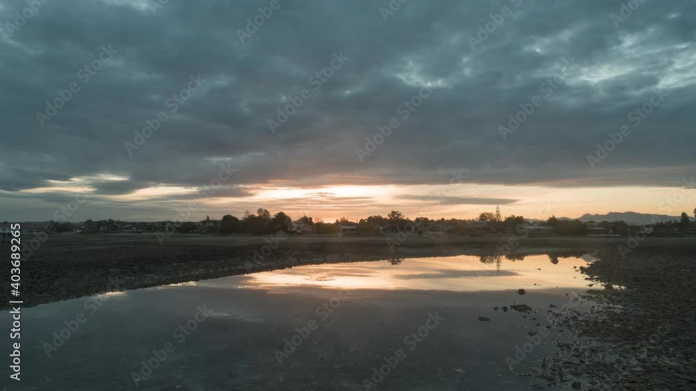 Time-lapse of the Waimea Inlet at low tide at sunset. The sunset reflected in a tide pool in the foreground. Mapua, New Zealand. Time-lapse of the Waimea Inlet at low tide at sunset. The sunset reflected in a tide pool in the foreground. Mapua, New Zealand.