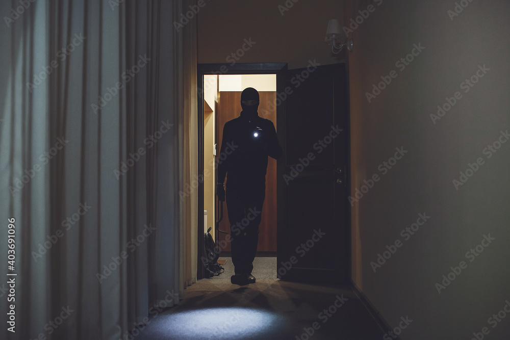 Full length of robber. Man with flashlight and bag in living room. Full length of robber. Man with flashlight and bag in living room.