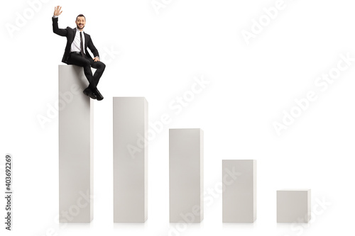 Businessman sitting on the highest column in a bar chart and waving