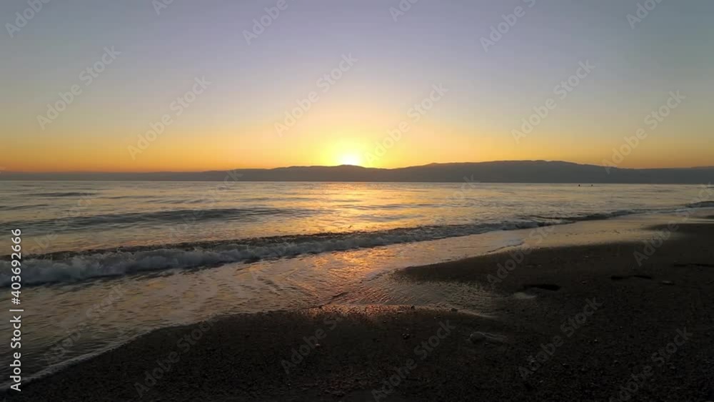 Sunrise in the Dead Sea, view from the beach on the waves