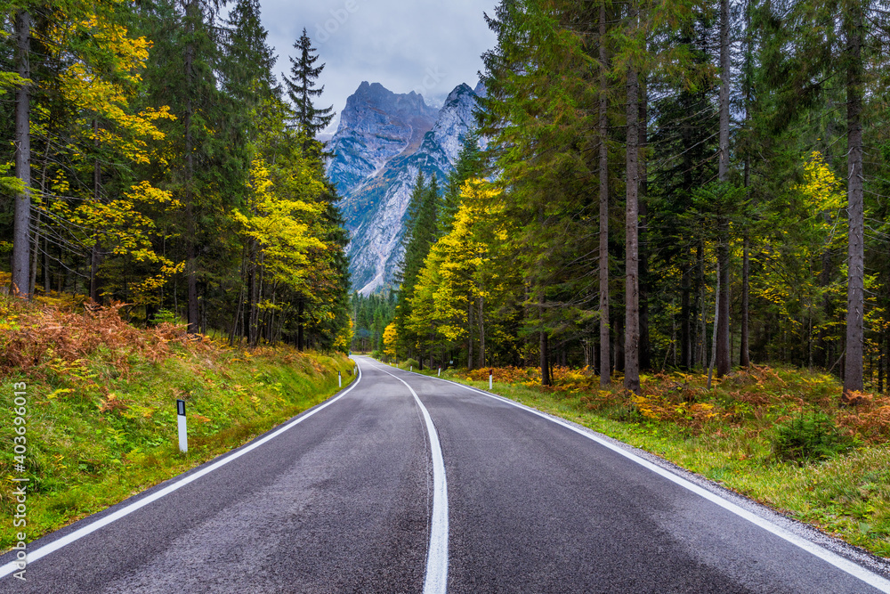 Fototapeta premium Mountain road. Landscape with rocks, sunny sky with clouds and beautiful asphalt road in the evening in summer. Vintage toning. Travel background. Highway in mountains.