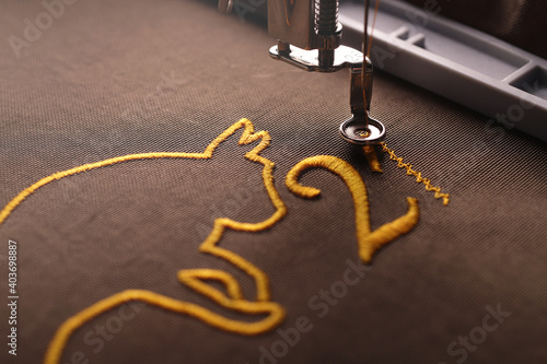 close up on golden ox symbol and number 21 stitched on brownish shiny olive fabric by an embroidery machine - selective focus chinese new year concept