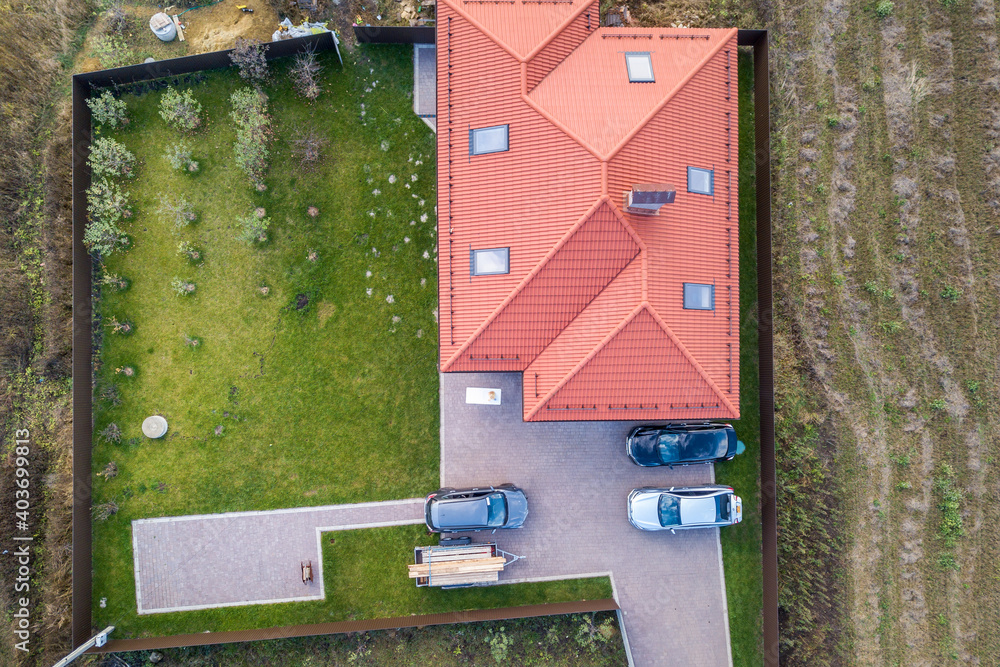 Aerial view of a private suburban house with parked cars in back yard.