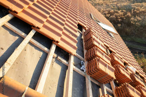 Stacks of yellow ceramic roofing tiles for covering residential building roof under construction.