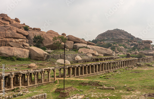 Wallpaper Mural Hampi, Karnataka, India - November 5, 2013: Sri Krishna tank in ruins. Brown stone long ruinous gallery runs diagonally through grassy field with brown boulders in back under silver sky. Torontodigital.ca