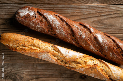 Crispy wheat and buckwheat baguettes on rustic wooden background.