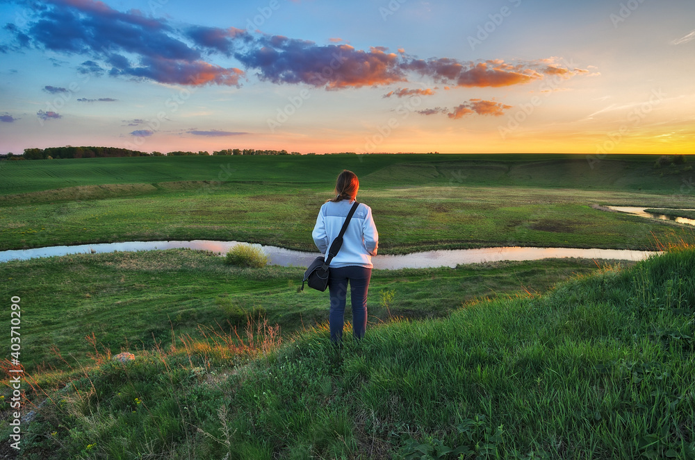 woman on the banks of the picturesque river. tourist is enjoying the morning landscape. colorful spring sunrise