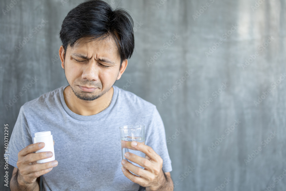Sick asian man holding glass of water taking pill, Take medicine to relieve illness, Health problems Sick asian man holding glass of water taking pill, Take medicine to relieve illness, Health problems