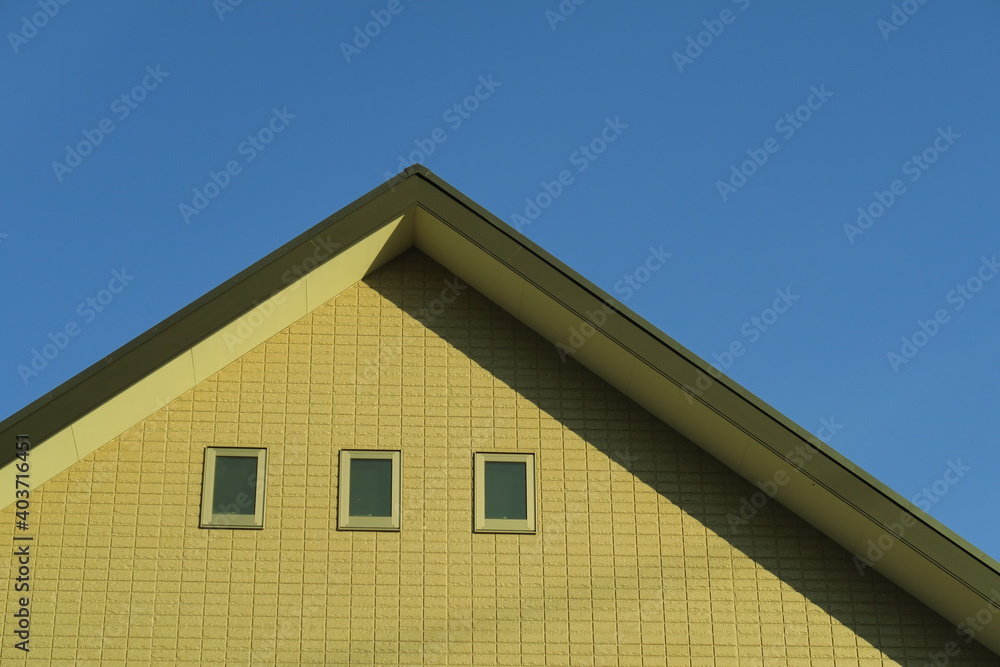 冬の西日の当たる新築住宅の壁と屋根と青空 冬の西日の当たる新築住宅の壁と屋根と青空