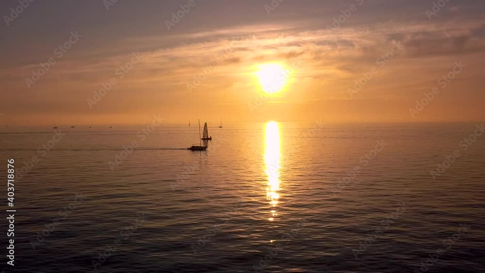Aerial wide shot of sailboats and yachts cruising along epic golden sunset with lighting water reflection. Aerial wide shot of sailboats and yachts cruising along epic golden sunset with lighting water reflection.