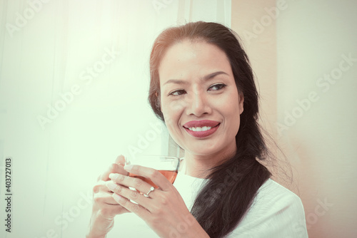 Fototapeta Naklejka Na Ścianę i Meble -  Beautiful black hair woman with red lips in white lace shirt standing by the window.