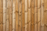 Full frame texture background of a wooden fence with natural wood grain planks, in bright sunlight