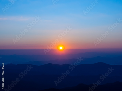 Sunrise in the morning is a red-orange circle on the horizon line. In the high view, we saw mountain silhouettes overlapping and the blue sky in the background.