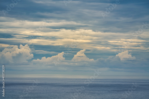 Blue sky with white cumulus clouds above the sea. The sea is a bit hazy. The landscape is from Hualien County, Taiwan looking towards the Pacific Ocean. photo