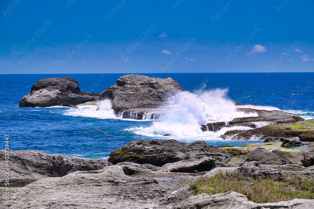 The waves hit the rocks and stirred up white waves. A fishing boat is at sea. Hualien County, Taiwan is a very popular place for leisure travel.