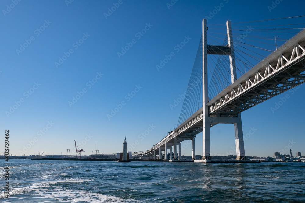 Naklejka premium 日本の横浜にあるベイブリッジ。海から見た青い空と橋の風景。