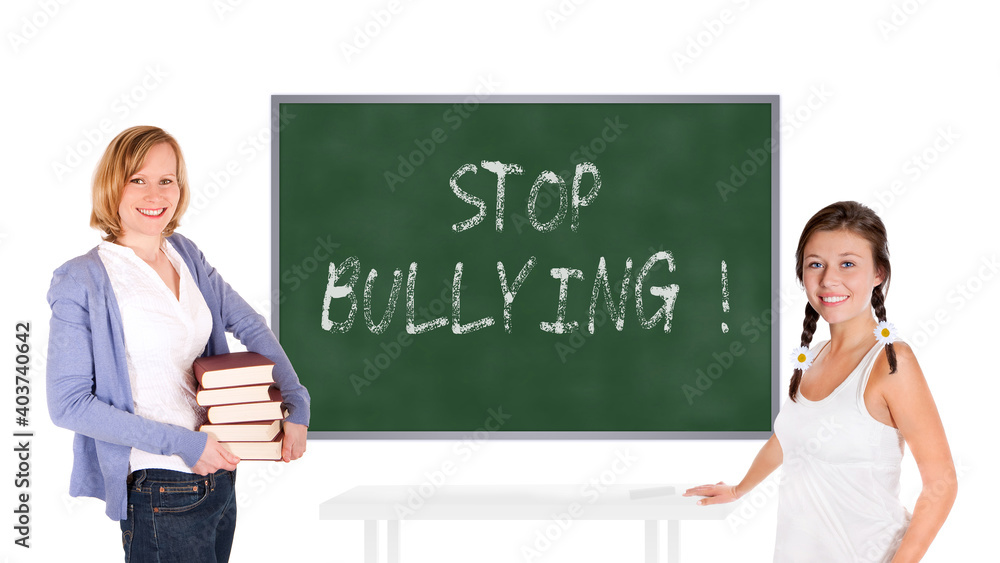 Young teacher and schoolgirl in front of a chalkboard, stop bullying is written on the board, isolated on white background Young teacher and schoolgirl in front of a chalkboard, stop bullying is written on the board, isolated on white background