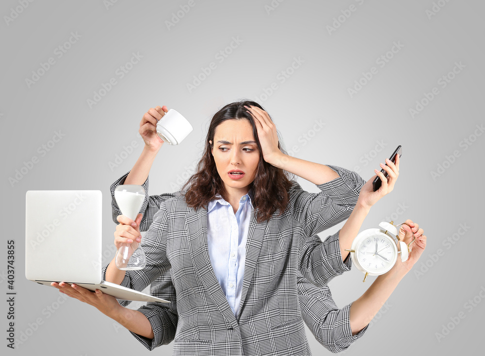 Stressed businesswoman with a lot of work to do on grey background