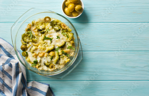 Broccoli, cauliflower, green olives and cheese homemde casserole on blue wooden table photo