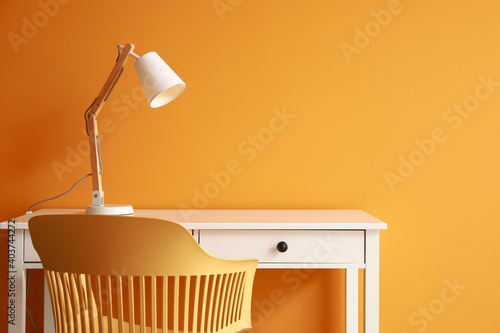 Modern table with lamp and chair near color wall photo