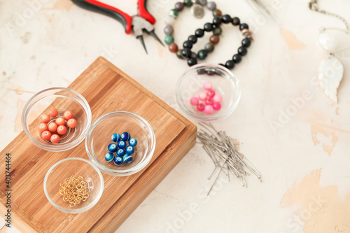 Workplace of jewelry designer with  tools and beads on light background