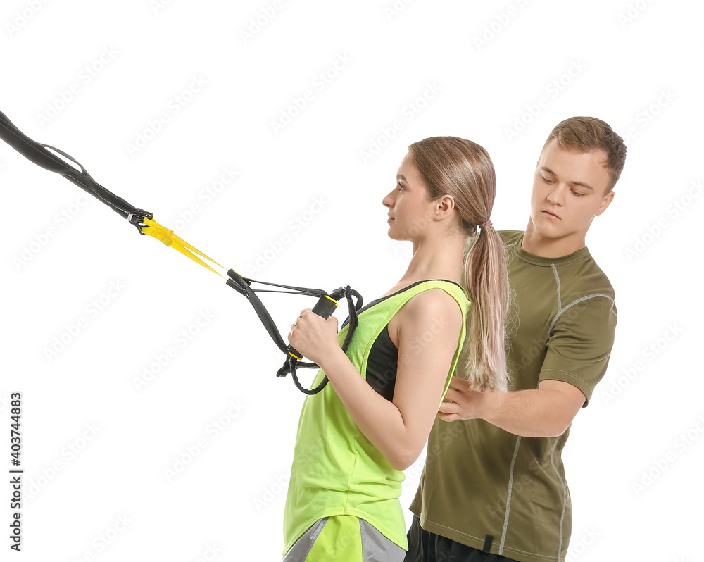 Coach helping young woman to train with TRX straps on white background Coach helping young woman to train with TRX straps on white background