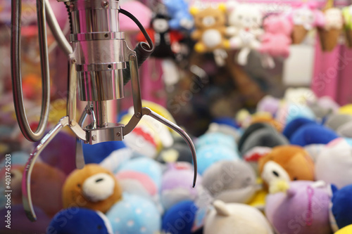 Claw capture device on a background of colorful soft toys in Japanese arcade machine games center. photo